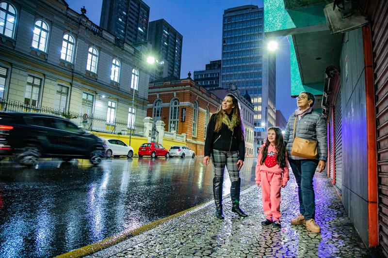 Rua Cruz Machado no Centro de Curitiba ganha nova iluminação em LED. Na imagem comerciante Fabiana Hannemann com a filha e Malu Gomes (jaqueta cinza), moradora da região - Curitiba, 18/07/2022 - Foto: Daniel Castellano / SMCS