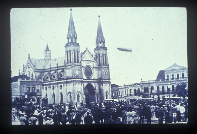 O dirigível alemão Hindenburg sobrevoando o Centro de Curitiba, em 1936, passando pela Praça Tiradentes e a Catedral. 